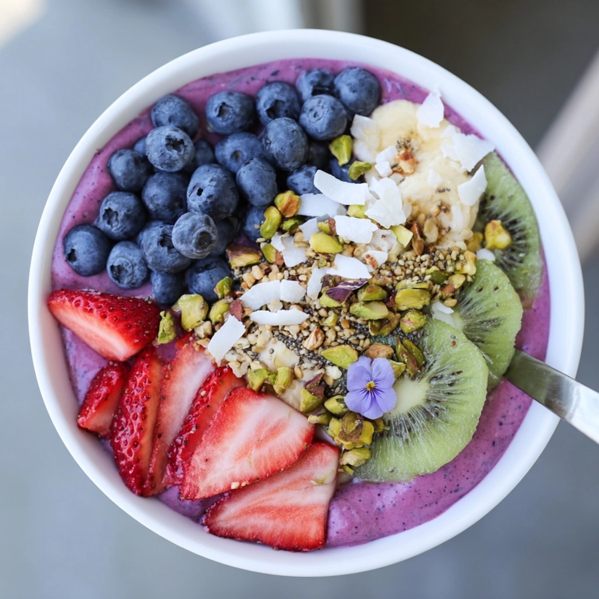 Close-up vibrant smoothie bowl, showcasing pistachio and purple yam swirls with berry toppings.