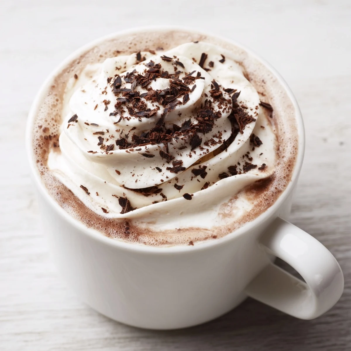 Steaming mug of hot chocolate with whipped cream, perfect for a cozy afternoon treat.