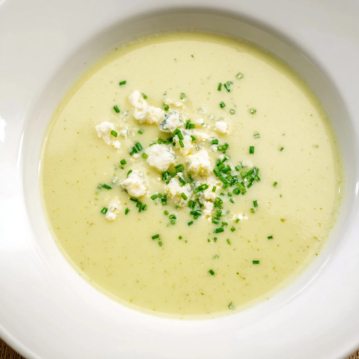 Creamy Celery and Stilton Soup, a rich and vibrant bowl, garnished with crumbled cheese and herbs.
