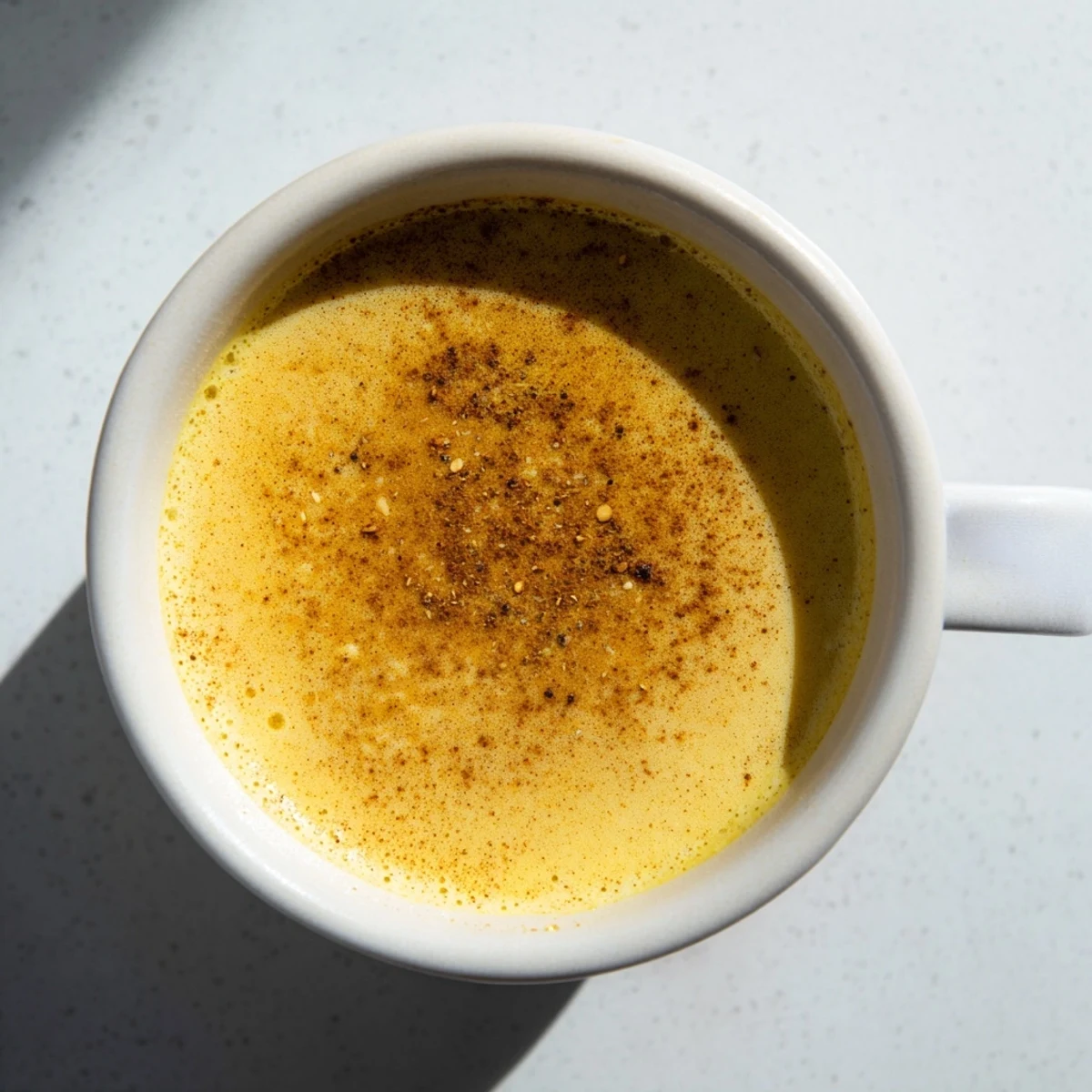 Freshly strained Spiced Golden Milk, a cozy vegetarian drink, promising soothing flavors and anti-inflammatory benefits.