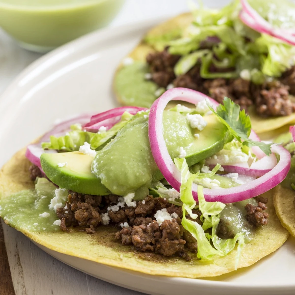 Sizzling beef tacos with vibrant salsa verde, red onion, creamy avocado, and crumbled cheese offer delightful textures.