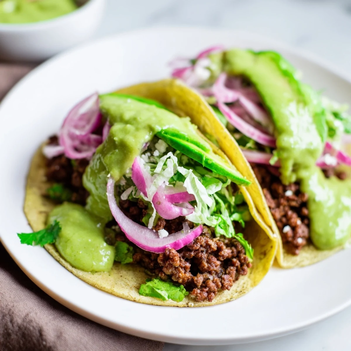 Fully loaded beef tacos, showcasing seasoned ground beef, fresh toppings, and a bright salsa verde, ready to eat.