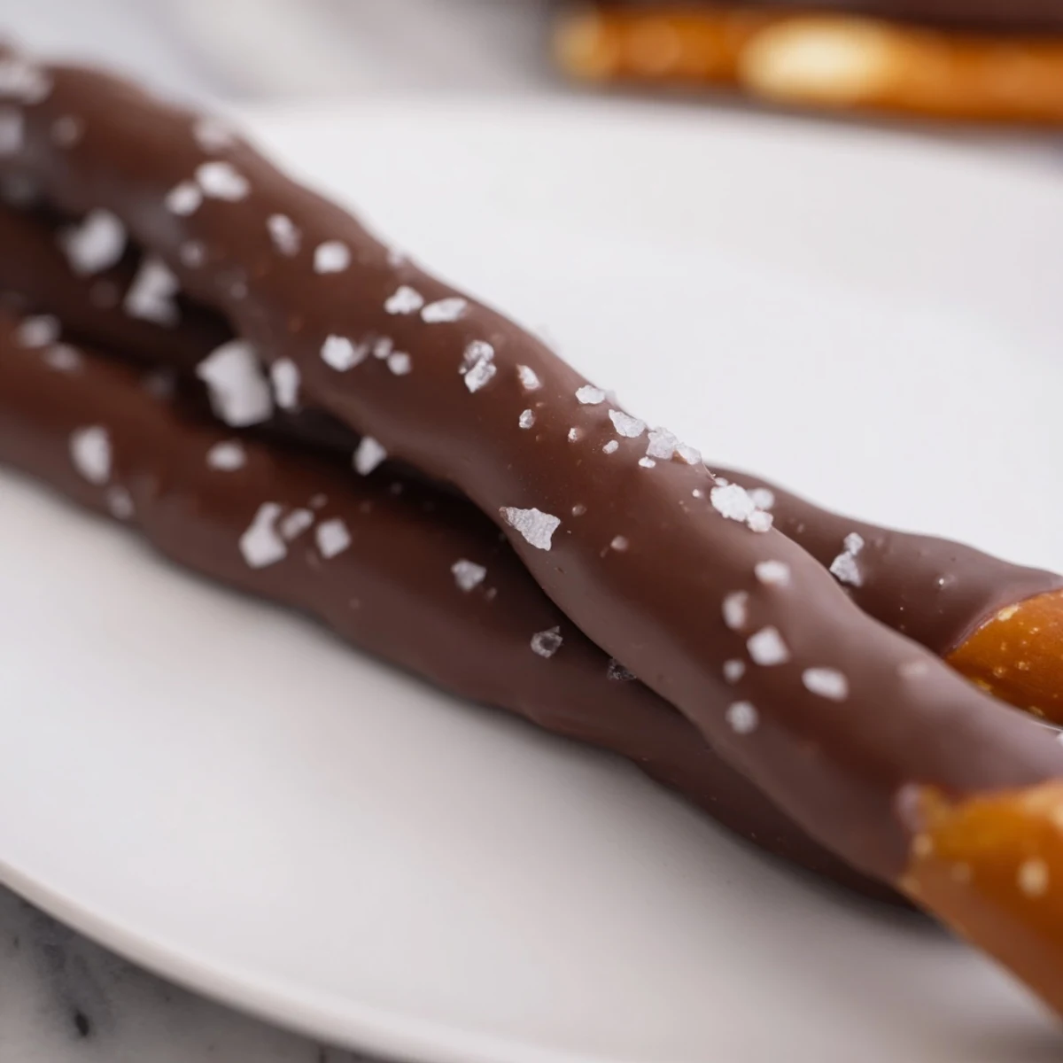 Close-up view of Chocolate Dipped Pretzels with Sea Salt, showing glossy dark chocolate drizzle and crunchy pretzel texture in a snackable arrangement.