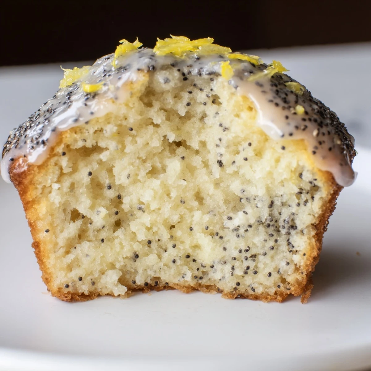 Freshly baked Lemon Poppy Seed Muffins with golden tops sit on a cooling rack, showcasing their moist crumb and citrusy zest.