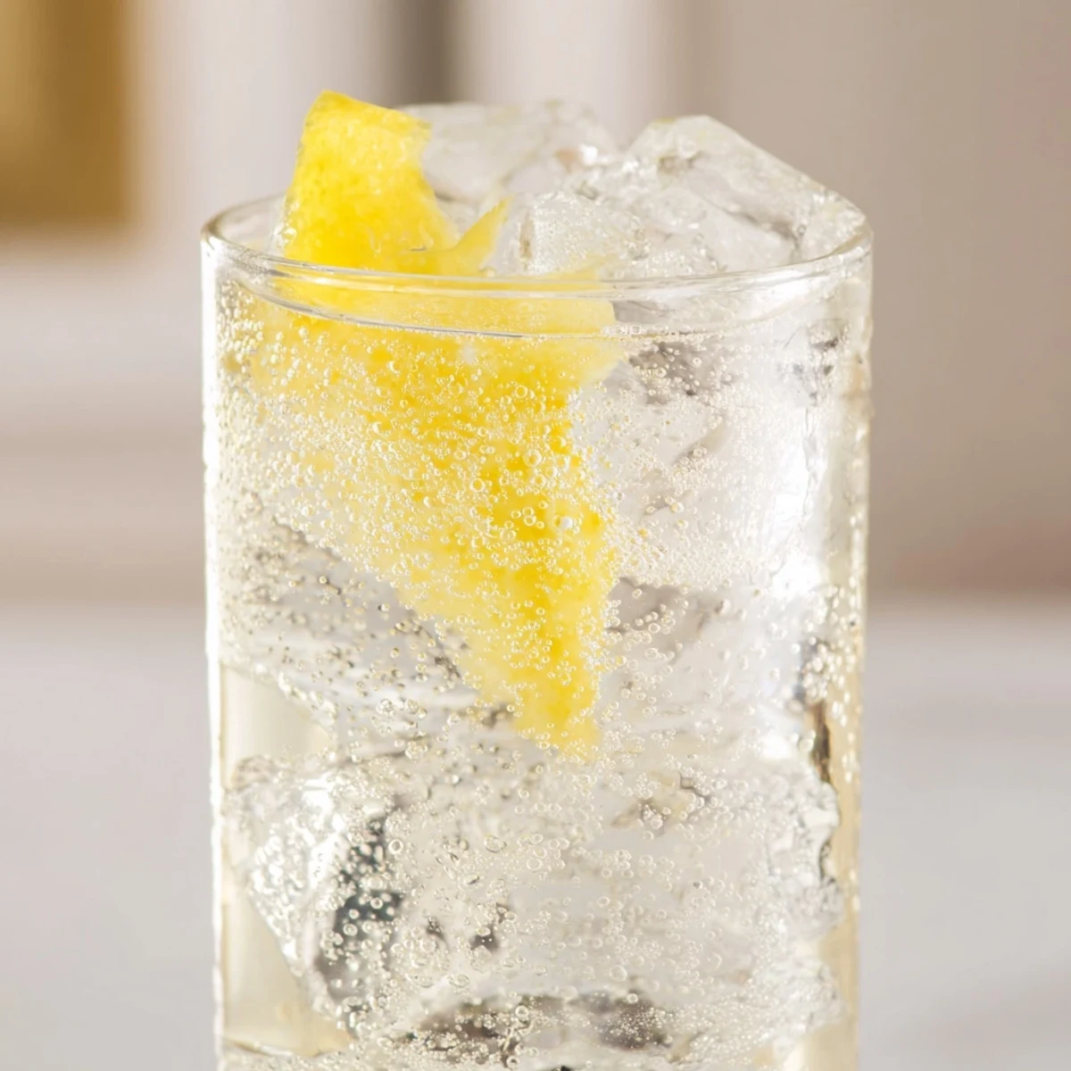 Lemon Twist Cocktail in a chilled highball glass with bubbly soda water, a lemon peel garnish, and condensation on the sides.