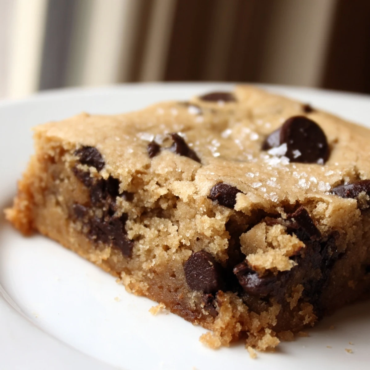 Freshly baked Chocolate Chip Cookie Bars cut into squares, served warm on a rustic wooden board.