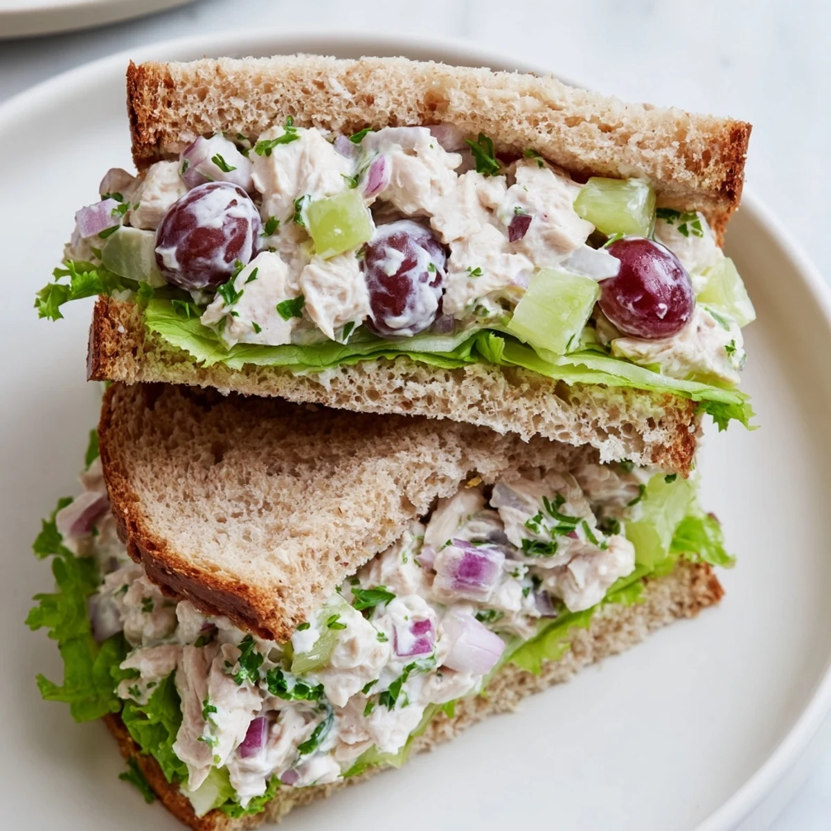 A classic Chicken Salad Sandwich with Grapes served on whole wheat bread with lettuce, showcasing creamy texture and crisp celery.