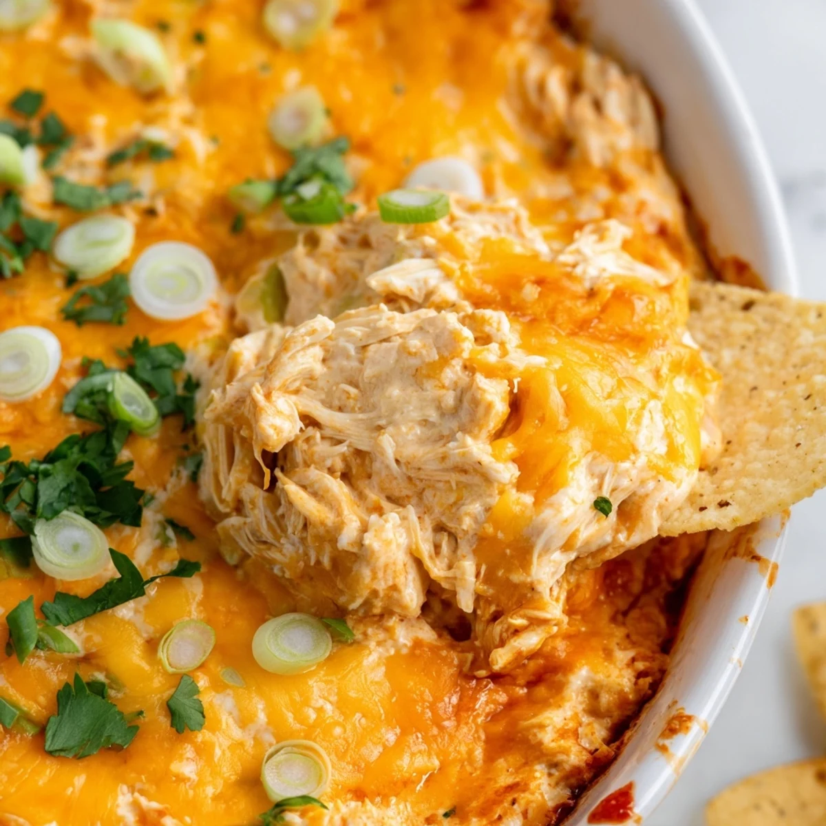 Golden-baked Spicy Buffalo Chicken Dip, bubbling with melty cheddar and mozzarella, served with crispy tortilla chips and fresh green onions.