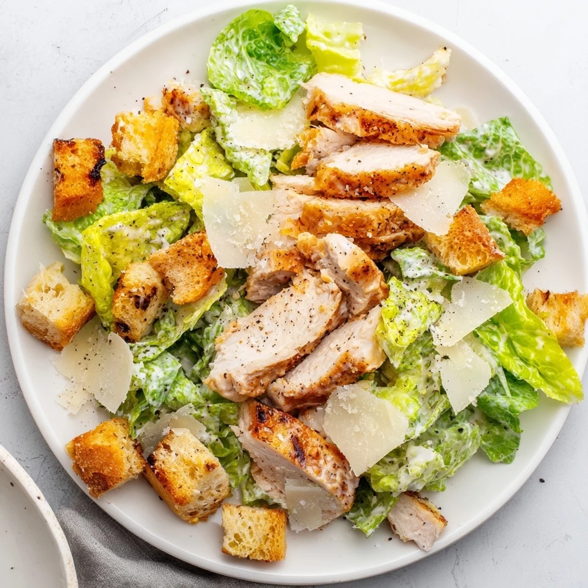 Homemade garlic croutons add crunch beside shaved Parmesan on this creamy Chicken Caesar Salad served ready to eat.