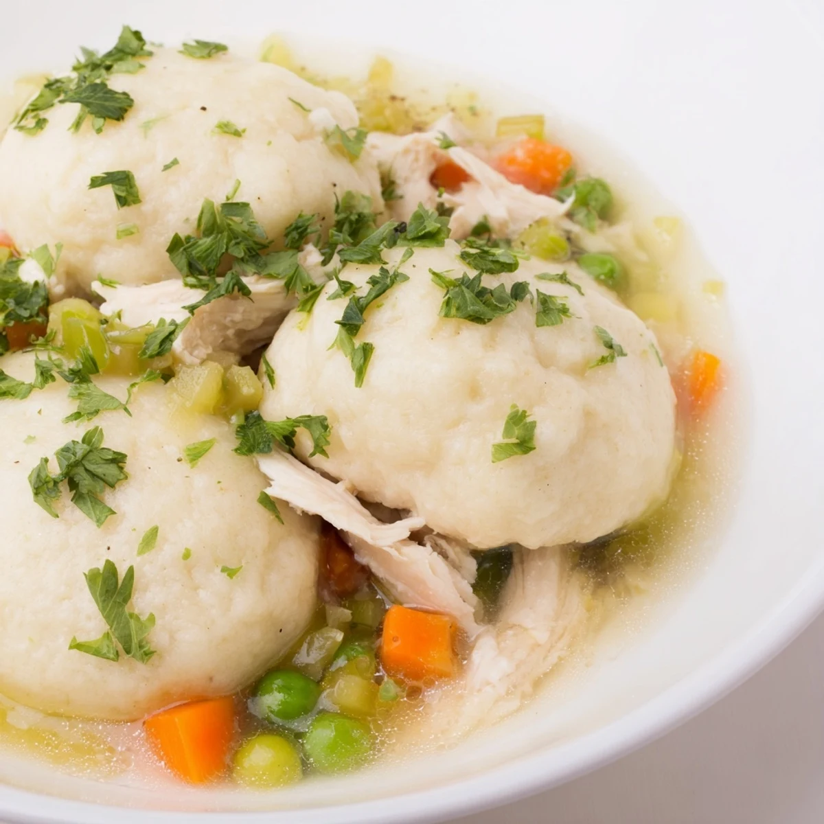 Comforting Chicken Soup with Fluffy Dumplings in a rustic bowl, steam rising from the savory broth and fluffy homemade dumplings.