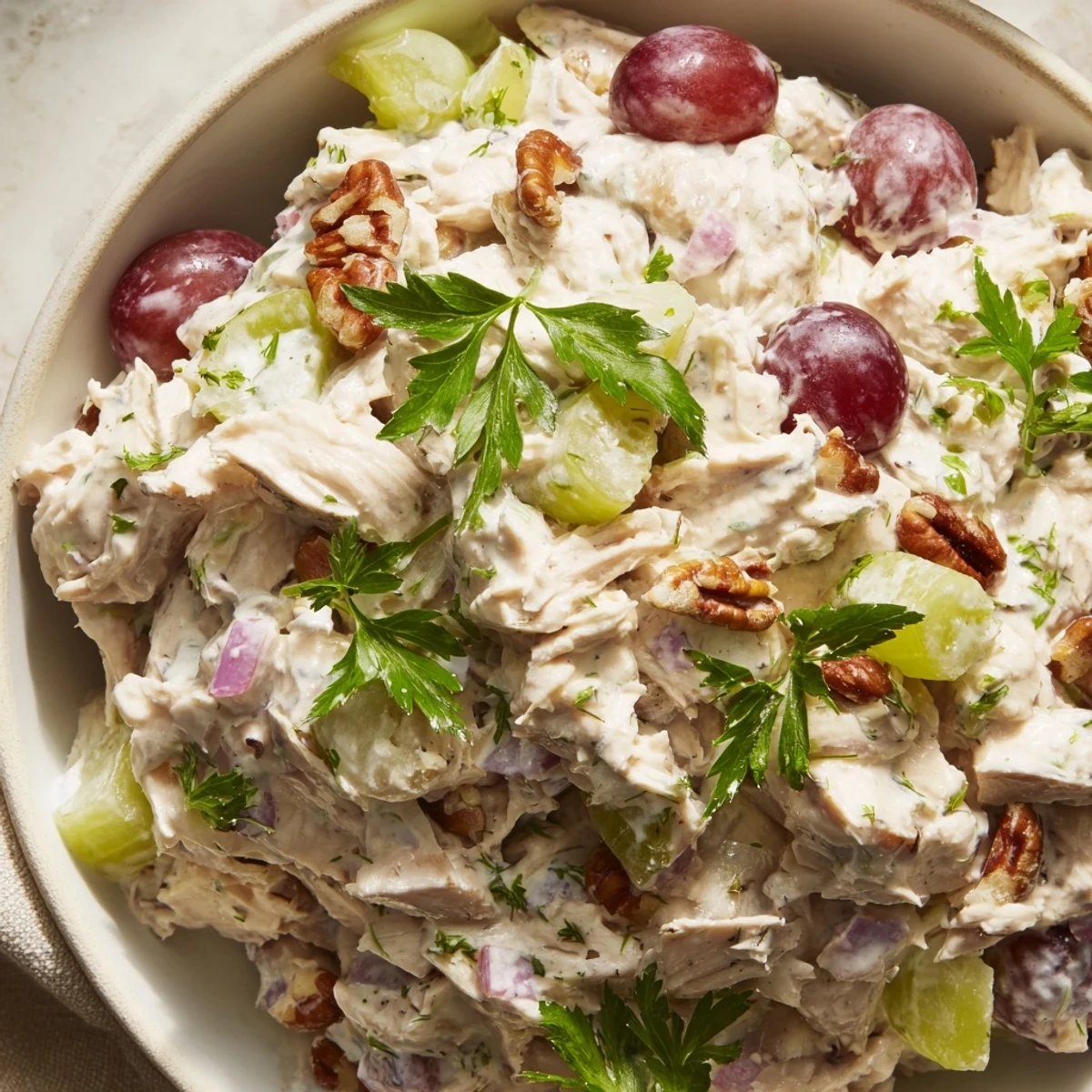 Freshly prepared Chicken Salad with Pecans showcases juicy chicken, chopped pecans, celery, and grapes, ready to be enjoyed at a sunny lunch.
