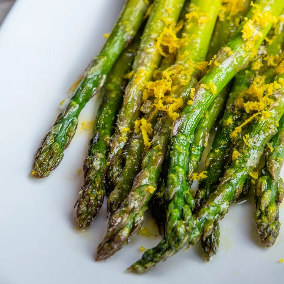 Golden-brown roasted asparagus with lemon zest and Parmesan on a rustic plate, garnished with fresh parsley and served alongside grilled chicken.  