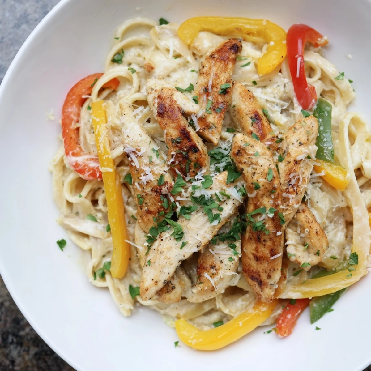 Sliced Cajun Chicken Alfredo with Bell Peppers in a creamy white sauce.