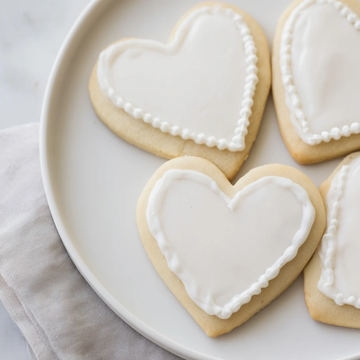 Freshly baked Heart Shaped Sugar Cookies with Royal Icing, decorated with red and white icing swirls, ready for gifting or parties.