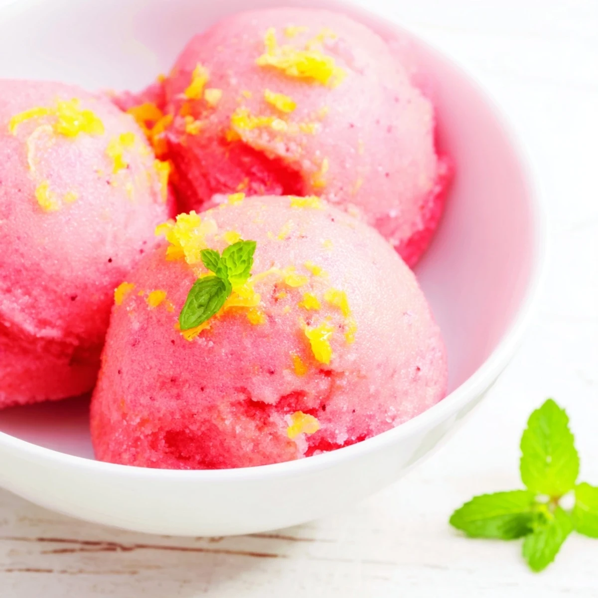 Bright pink lemonade sorbet overflowing from a serving dish, flecked with mint and ready to cool down a crowd.