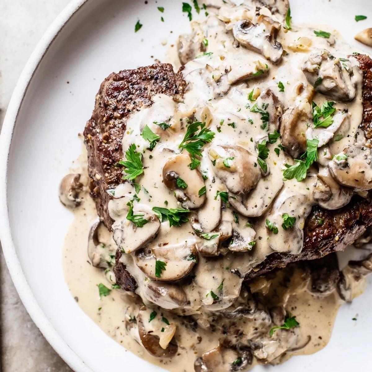 Close-up view of pan-seared steak Diane with mushrooms and brandy sauce, steam rising from the hot, glossy brown sauce pooling around the meat.