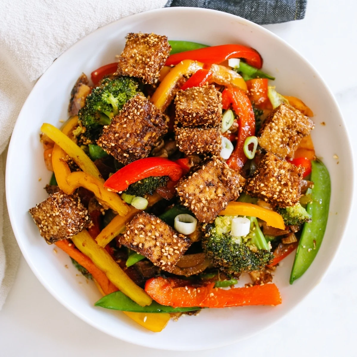 Crispy coconut tofu with stir fry veggies, finished with sesame seeds and ready to serve over rice.