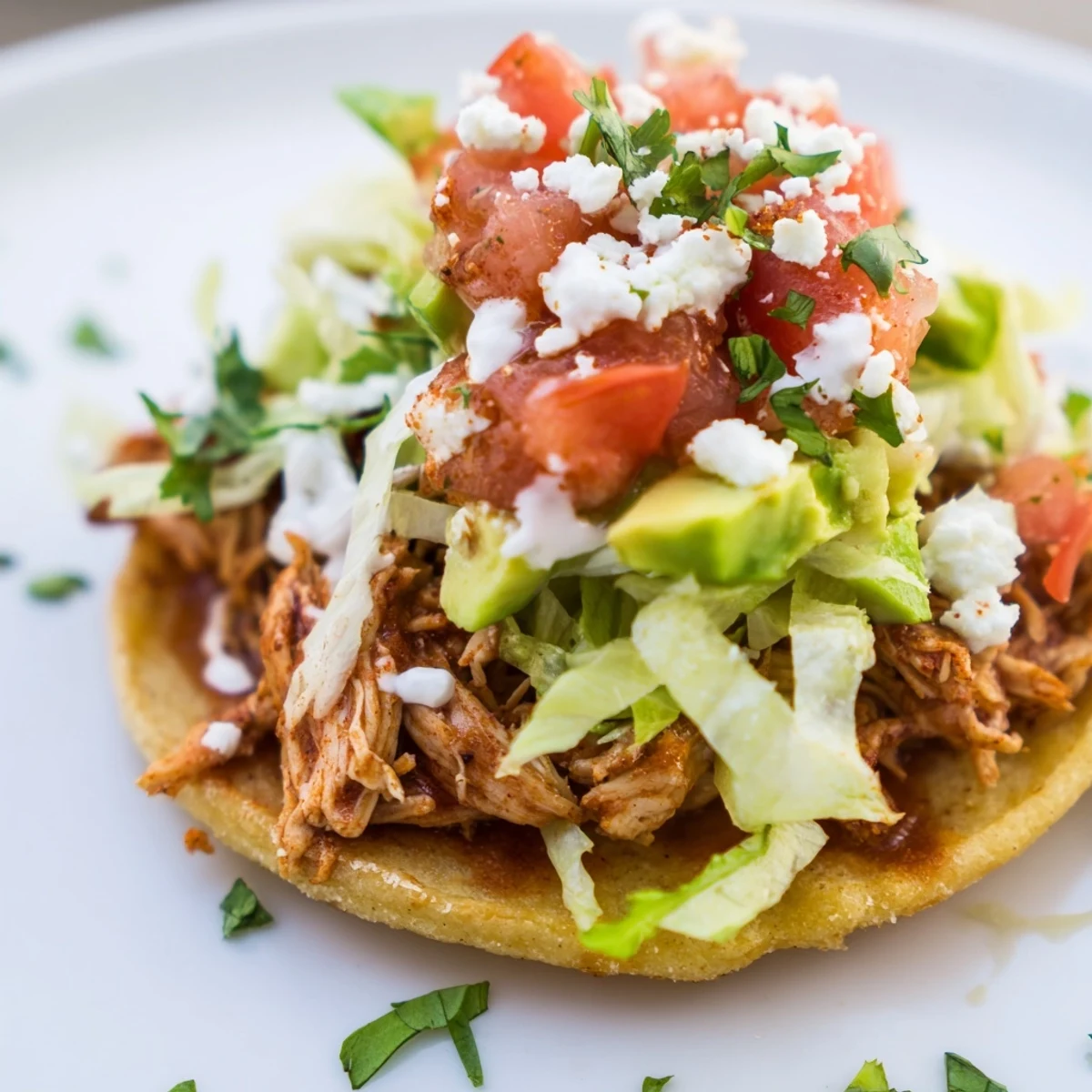 A platter of mini chicken tostadas garnished with cilantro and sour cream, ready to serve.