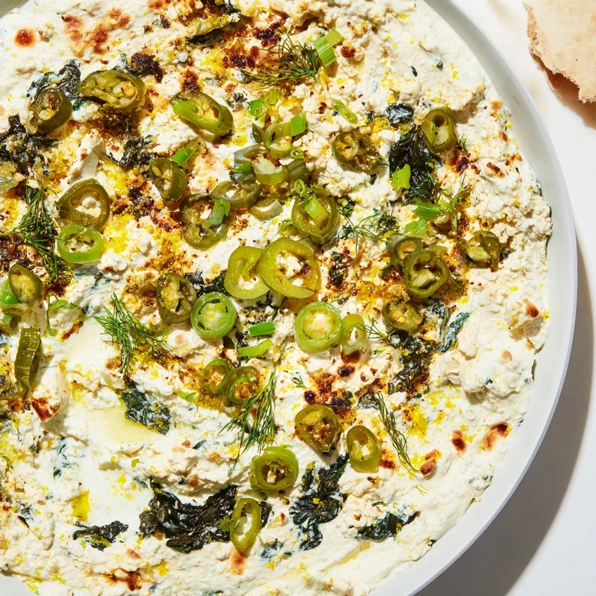 Warm Spinach and Pepperoncini Baked Feta Dip served in a rustic baking dish with crusty bread.