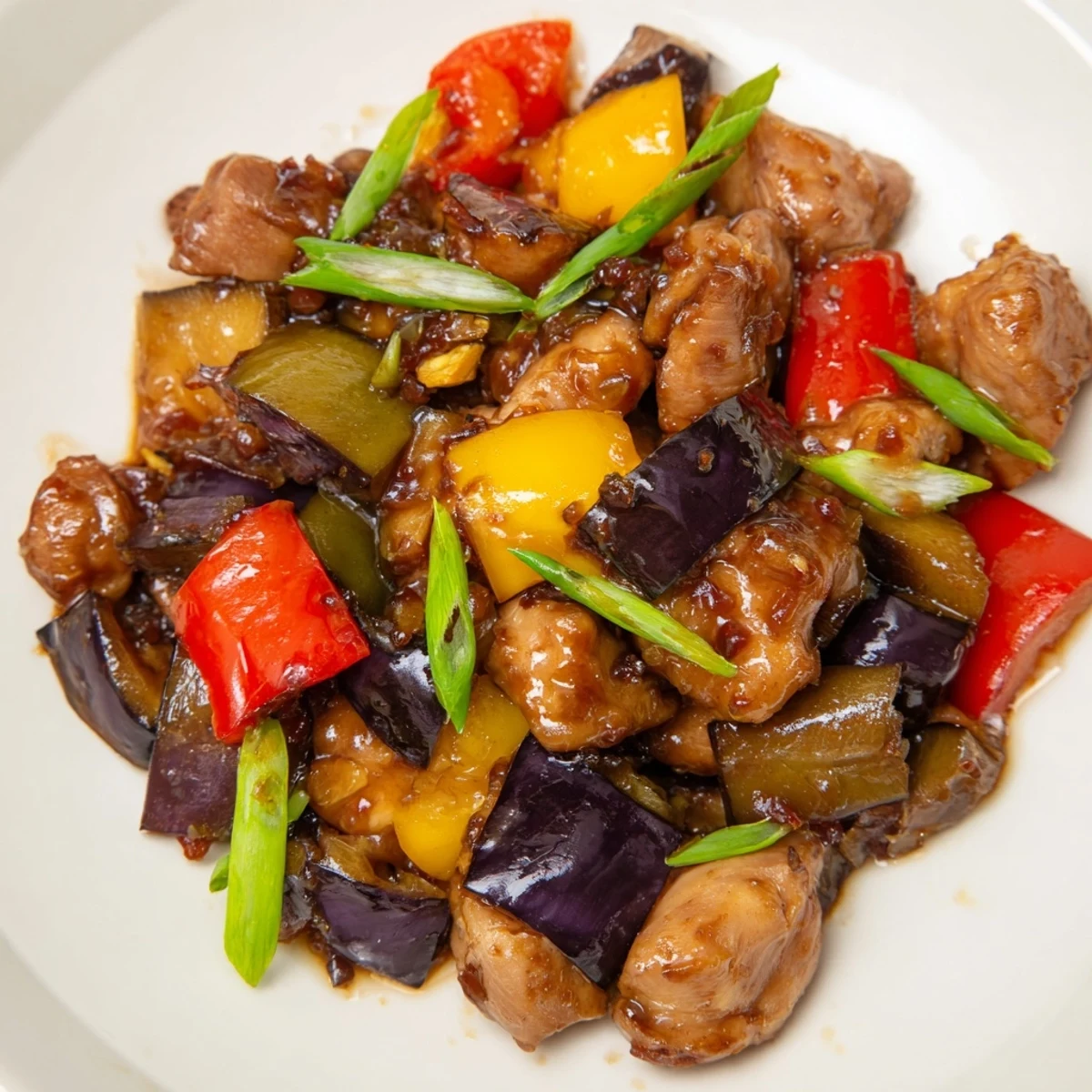 Tangy Black Vinegar Chicken With Bell Peppers And Eggplant served over white rice with chopsticks resting nearby.