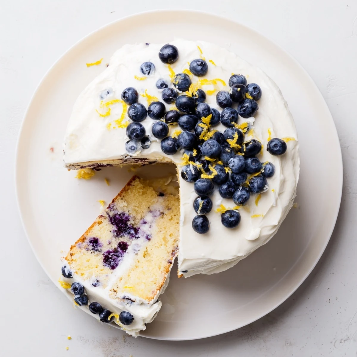 Freshly baked Lemon Blueberry Cake with Cream Cheese Frosting, featuring bright lemon zest and plump blueberries.