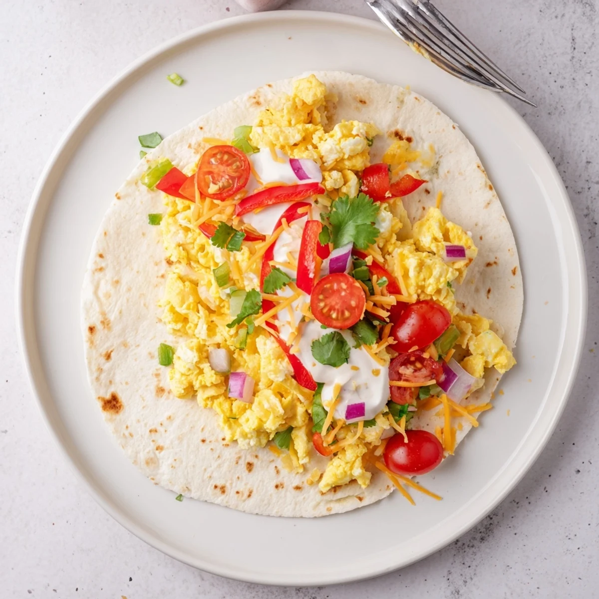 Fluffy scrambled eggs and savory vegetables rolled in a soft tortilla, perfect for a quick vegetarian breakfast.