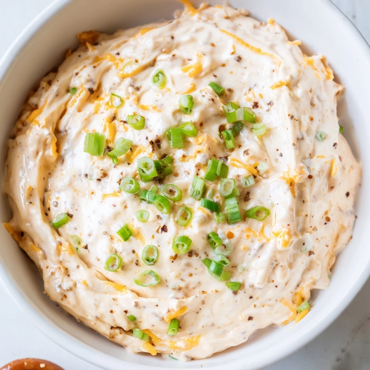 Creamy savory pretzel dip with melted sharp cheddar, fresh chives, and Dijon mustard served alongside warm soft pretzels for party dipping