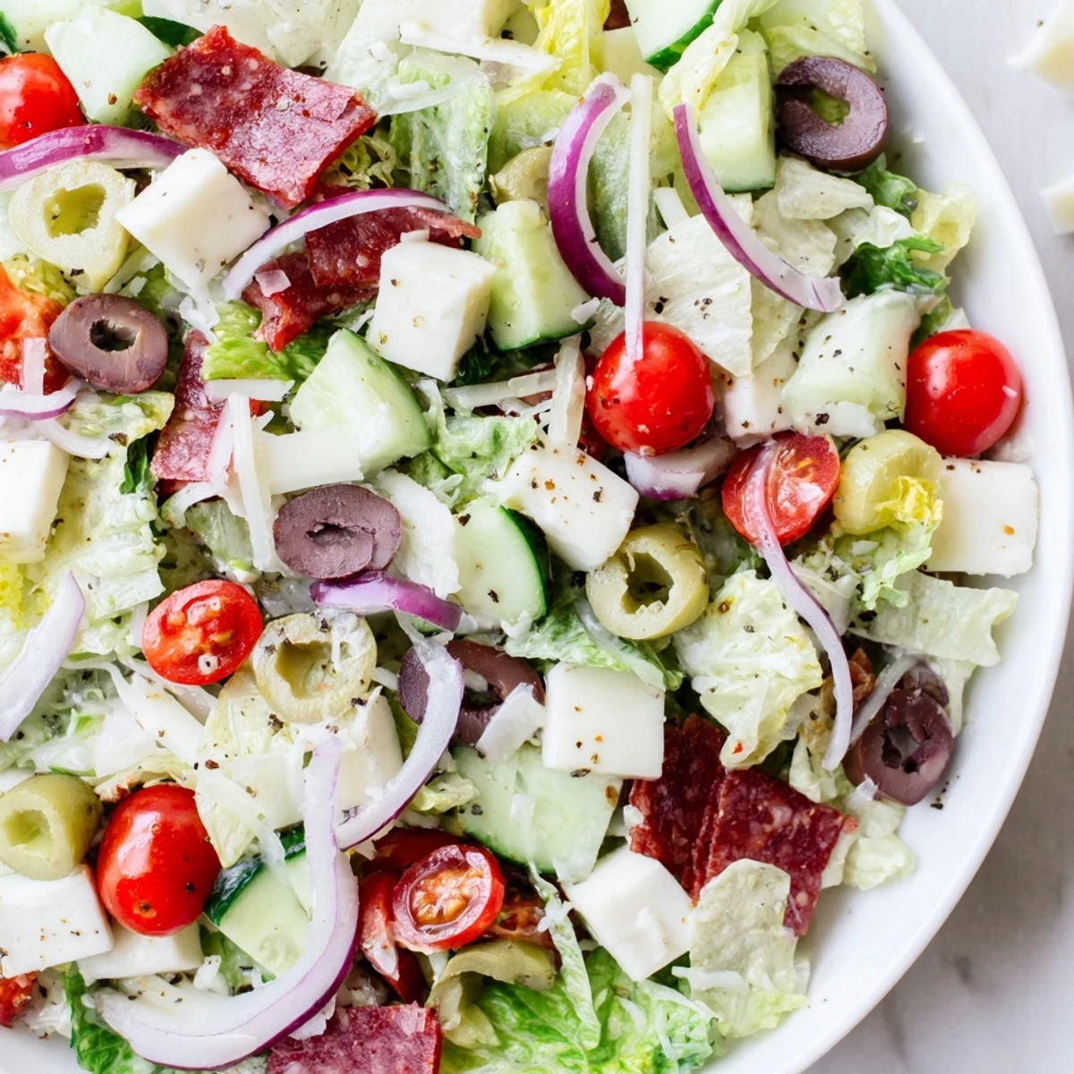 Fresh Italian chopped salad featuring cherry tomatoes, cucumber, pepperoncini, and shaved Parmesan tossed in tangy vinegar dressing.