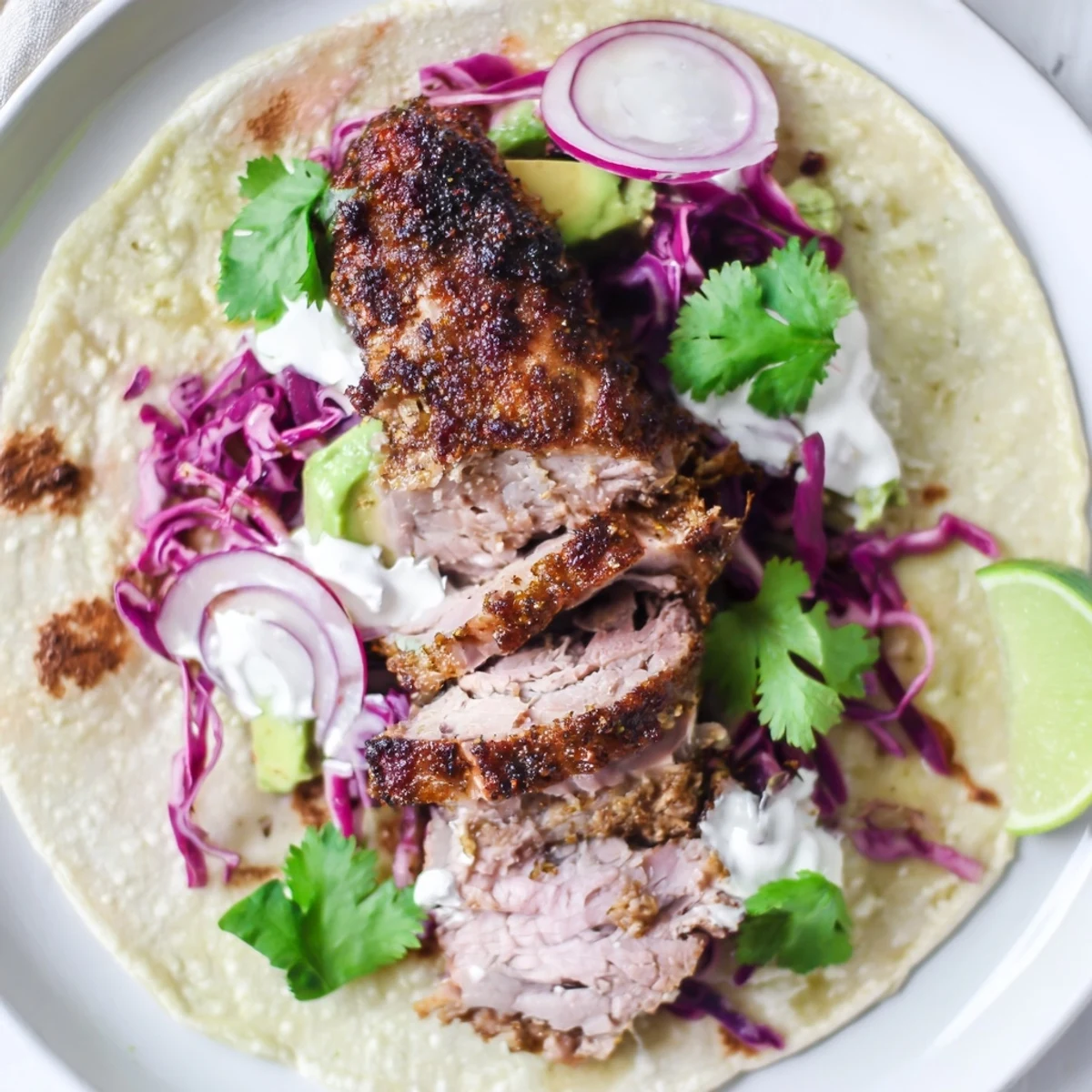 Succulent cumin crusted leg of lamb tacos topped with fresh avocado and cilantro