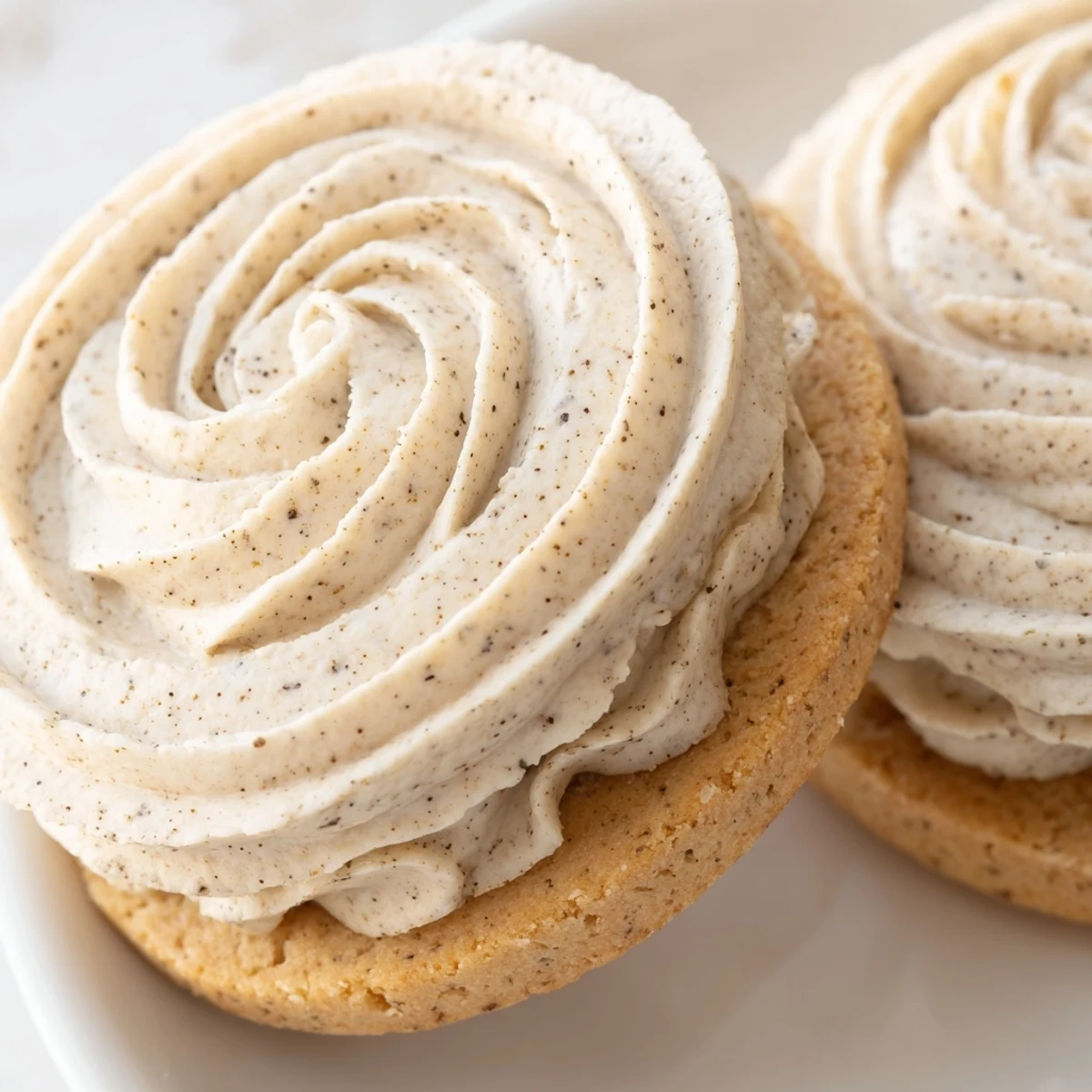 Buttery chai shortbread cookie sandwiches filled with spiced cream atop a rustic wooden serving board