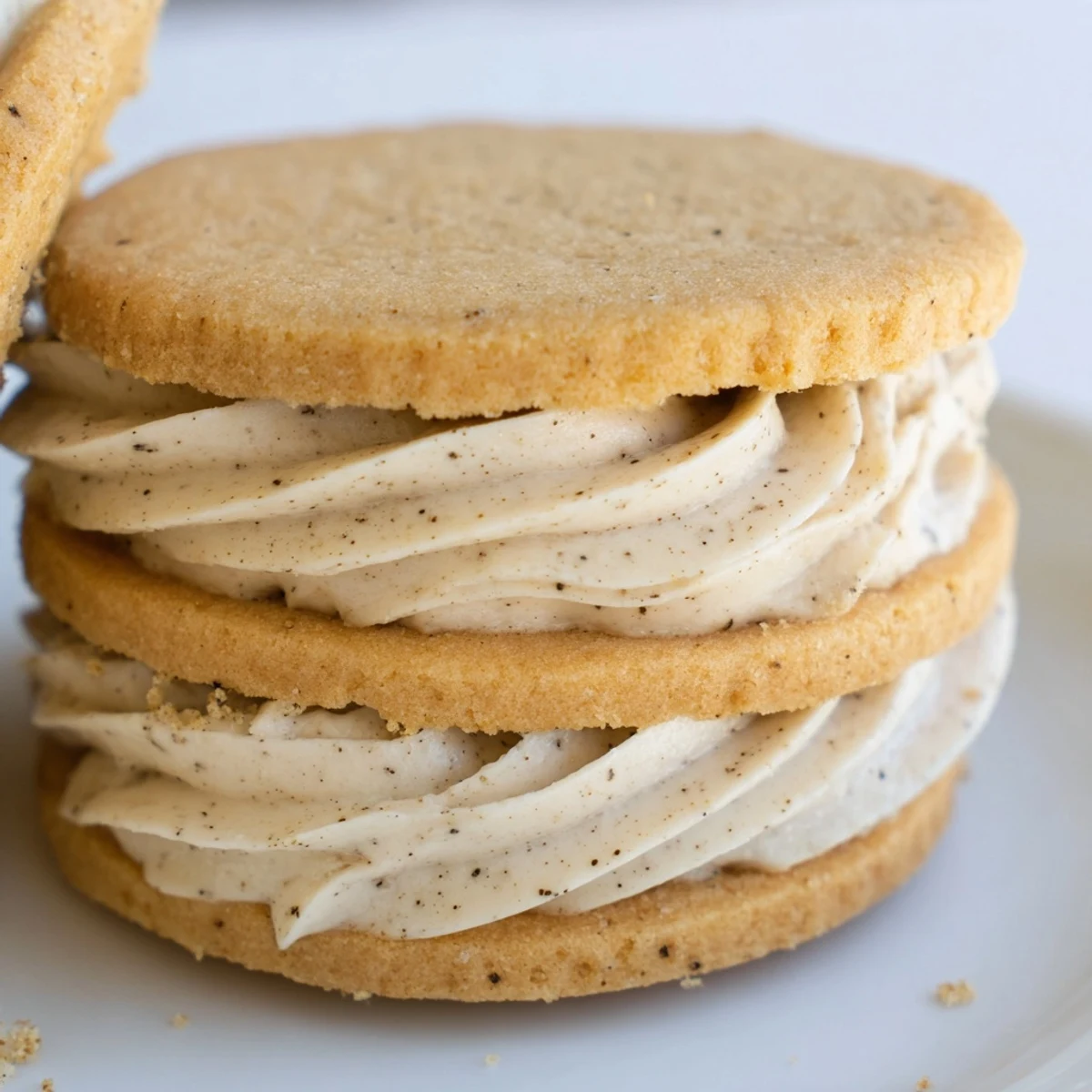 Golden chai shortbread cookie sandwiches with creamy spiced buttercream filling between two delicate cookies