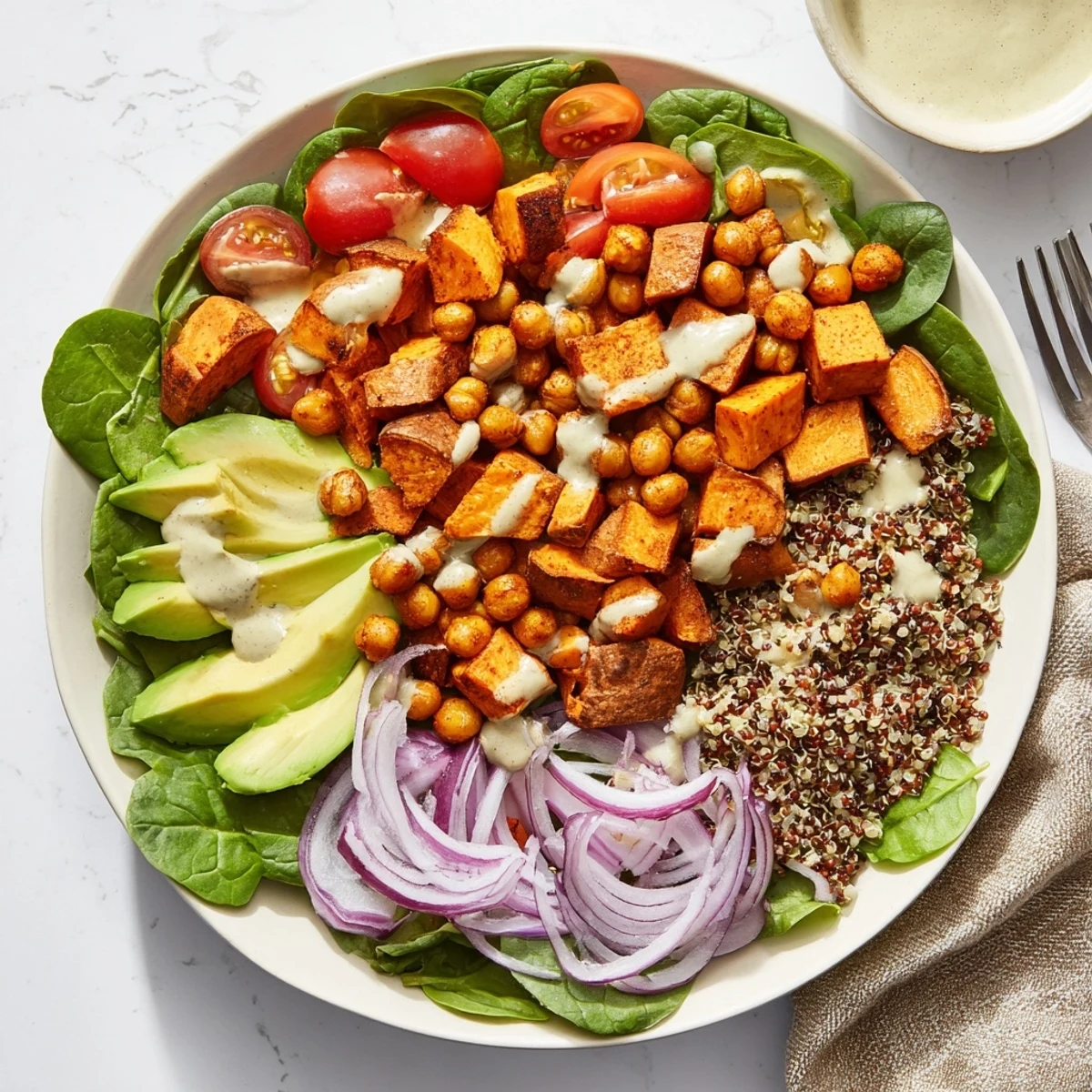 Vibrant lunch bowl featuring tender roasted sweet potatoes and chickpeas with a velvety tahini dressing over greens