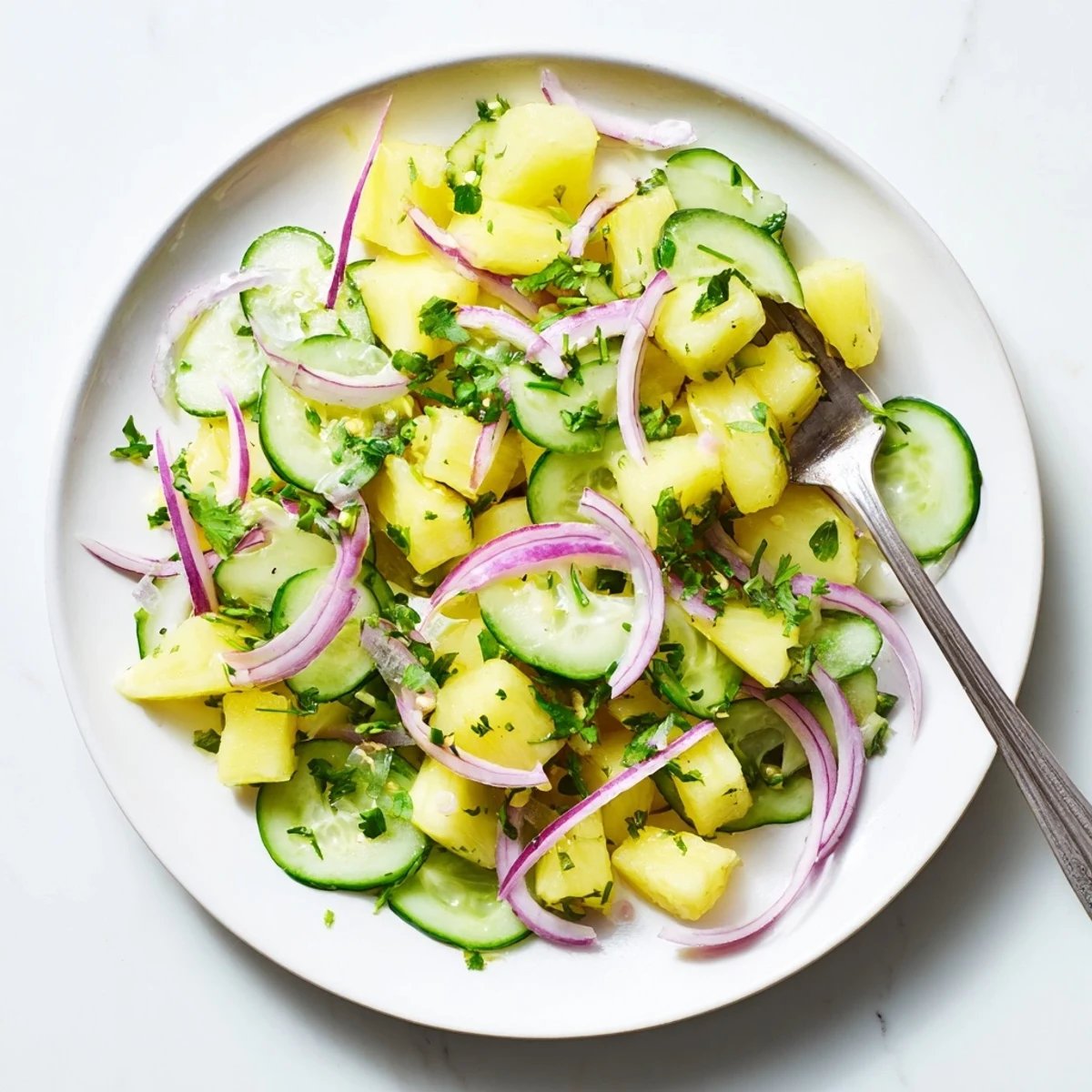 Fresh pineapple cucumber salad with lime dressing, cilantro, and red onion in a bowl