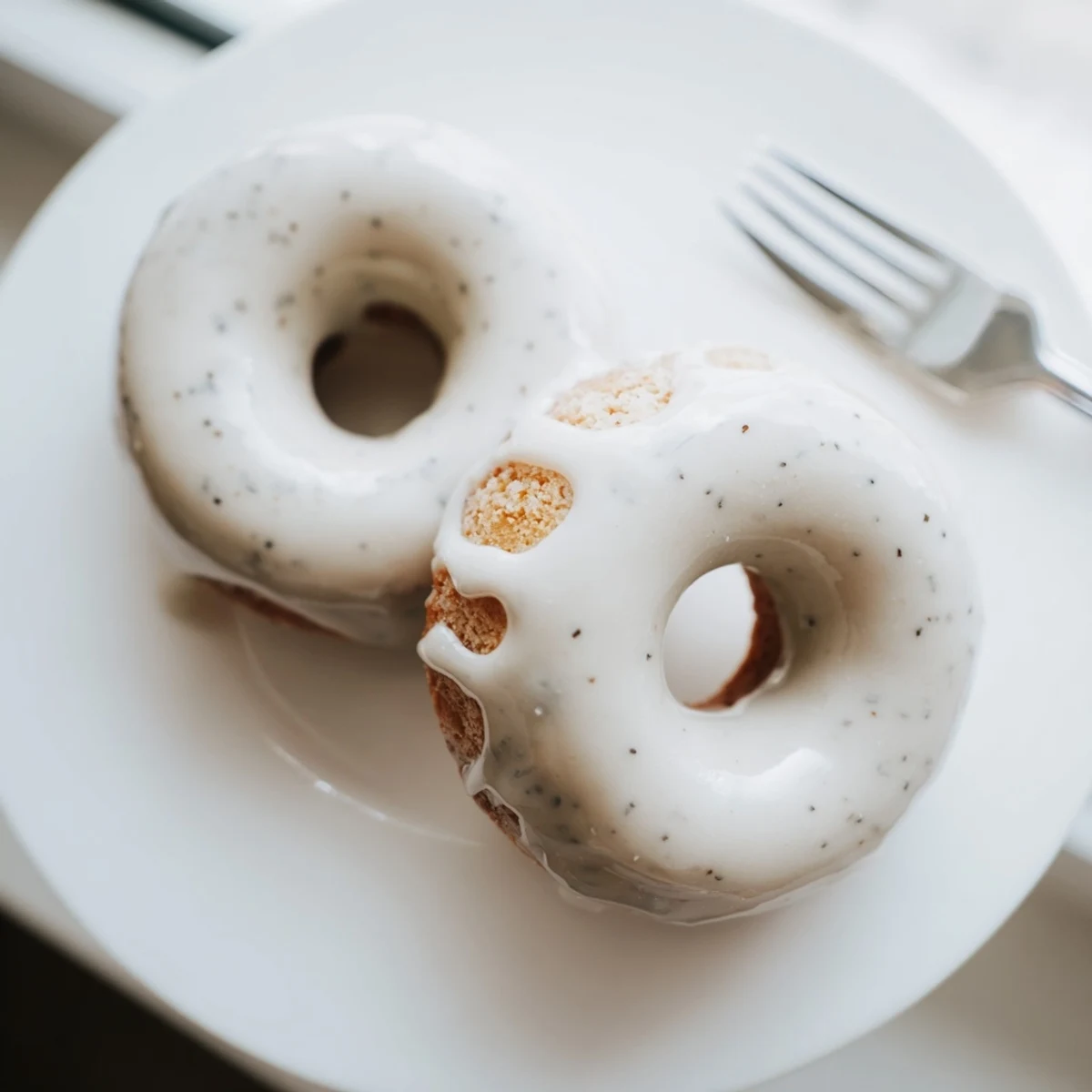 Chewy tea-infused donuts arranged on a white plate with Earl Grey glaze dripping down the sides