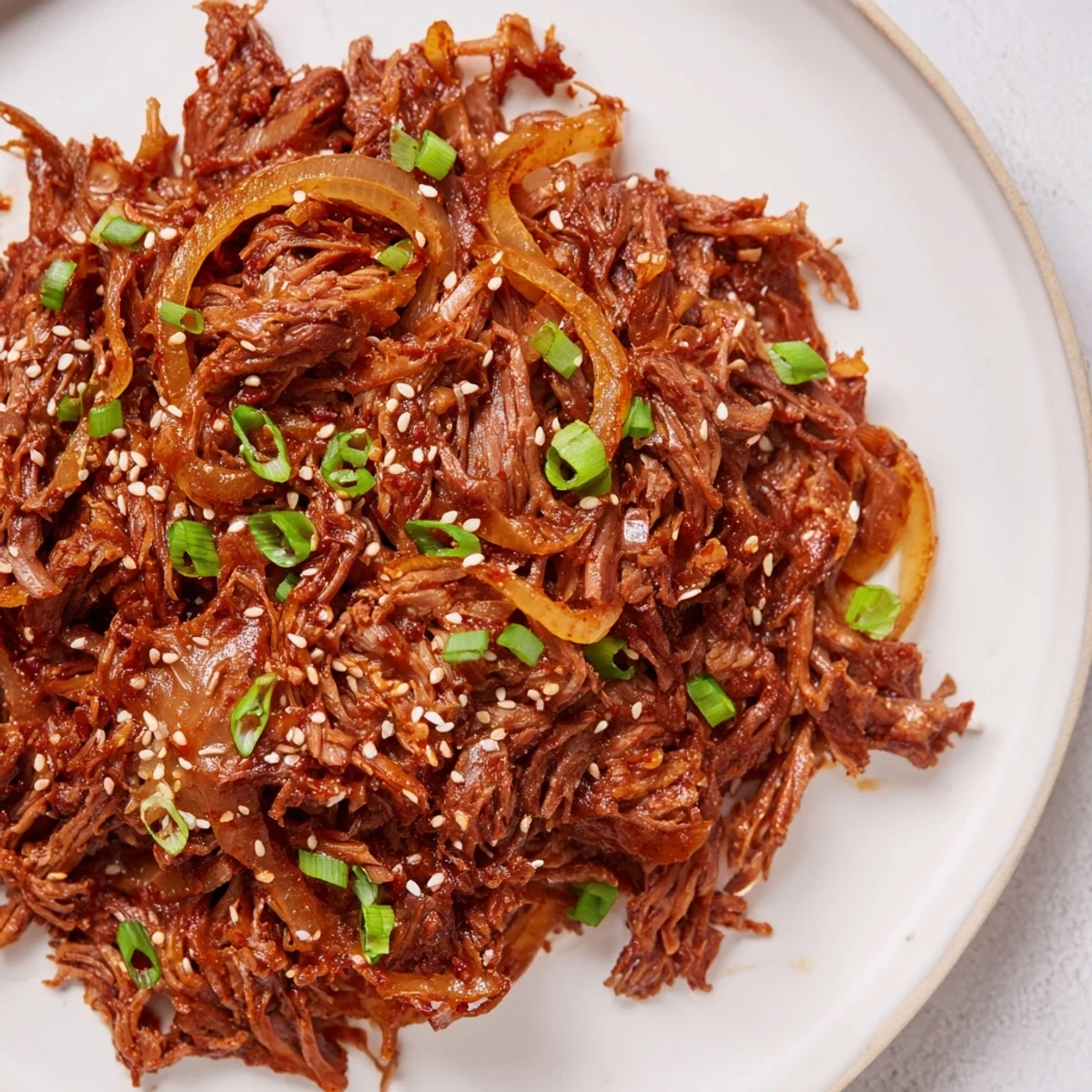 Shredded Korean beef slow cooked in savory sweet sauce garnished with green onions