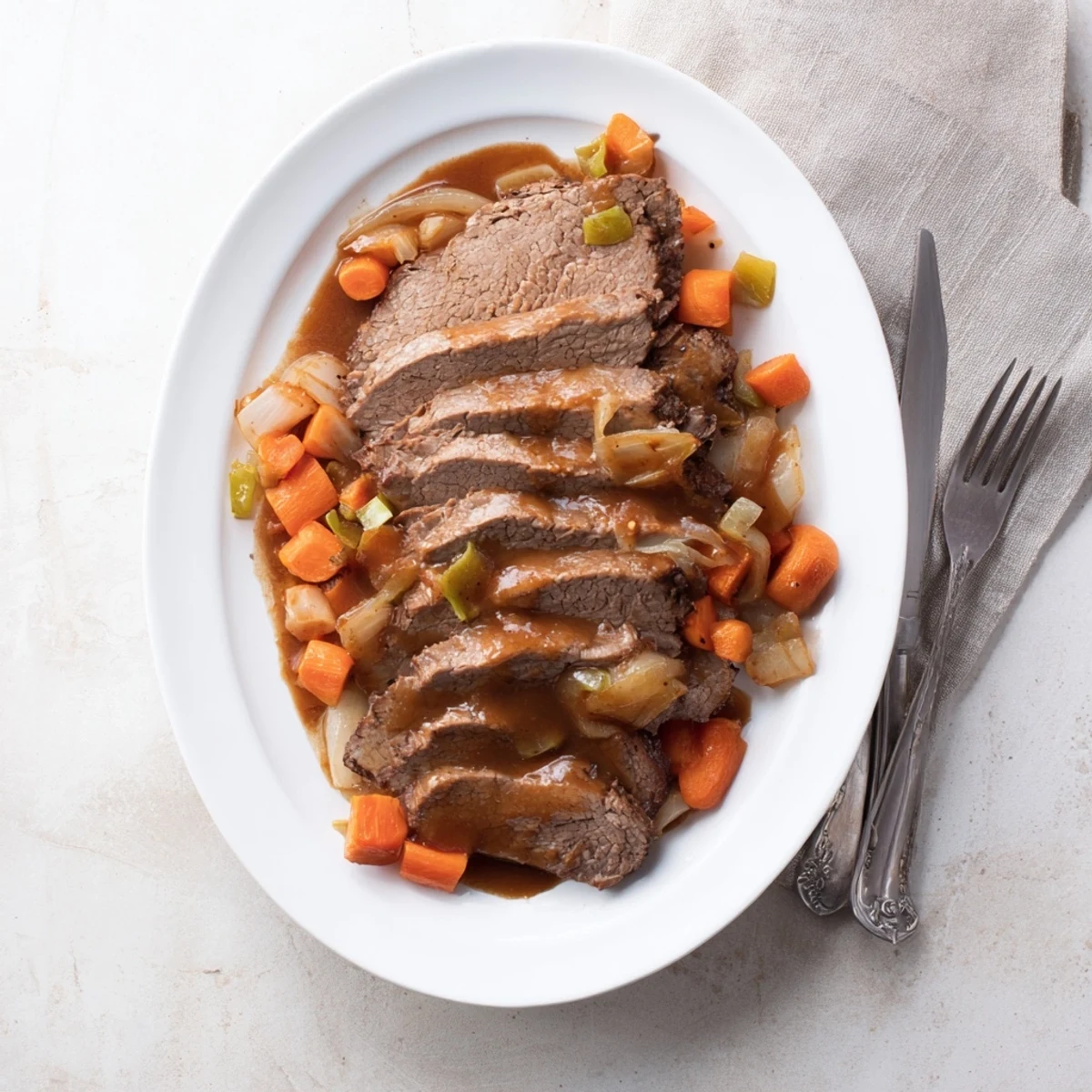Slow cooker beef brisket with tender sliced meat surrounded by carrots and onions in rich savory sauce
