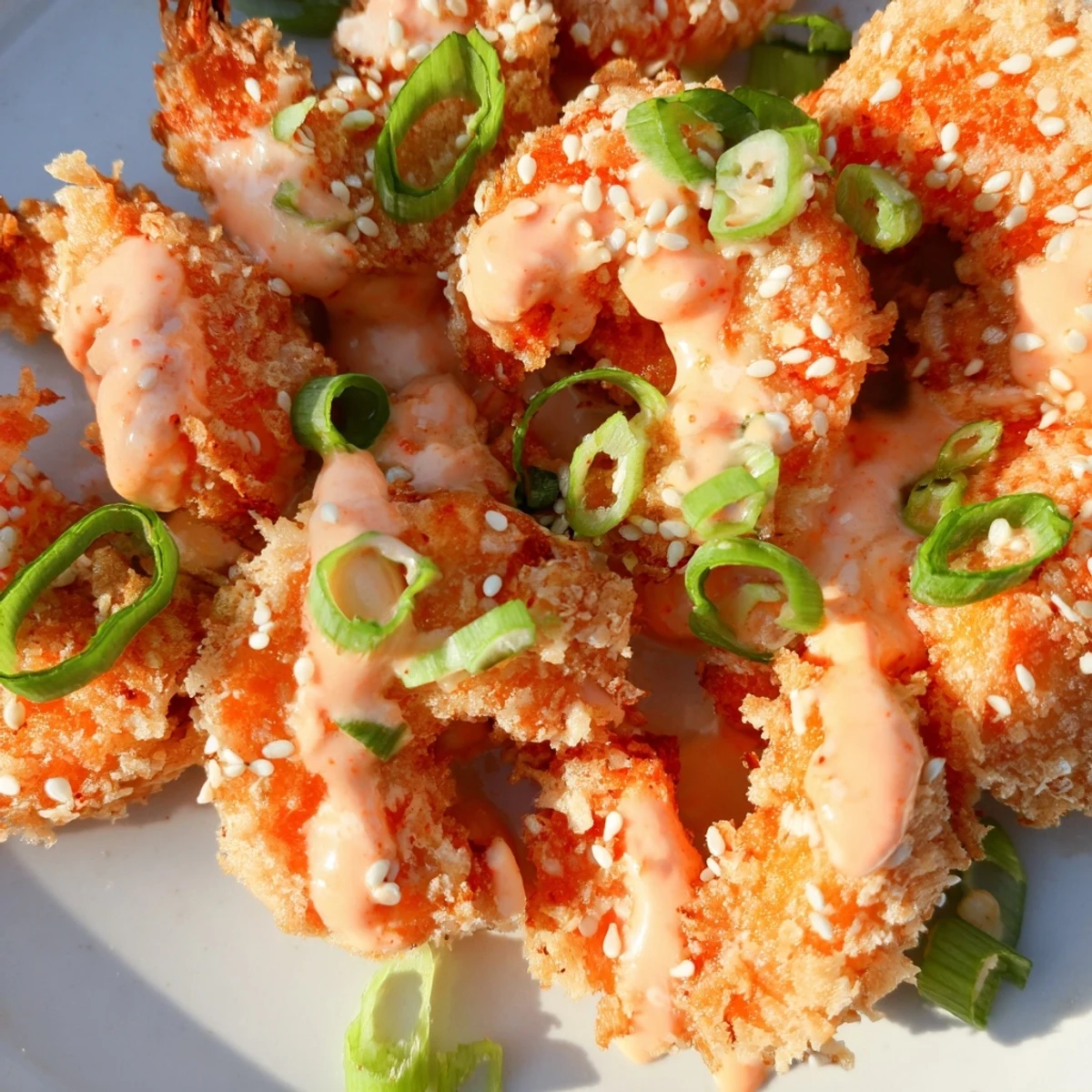 Golden crispy Bang Bang Shrimp coated in creamy spicy sauce with green onion garnish