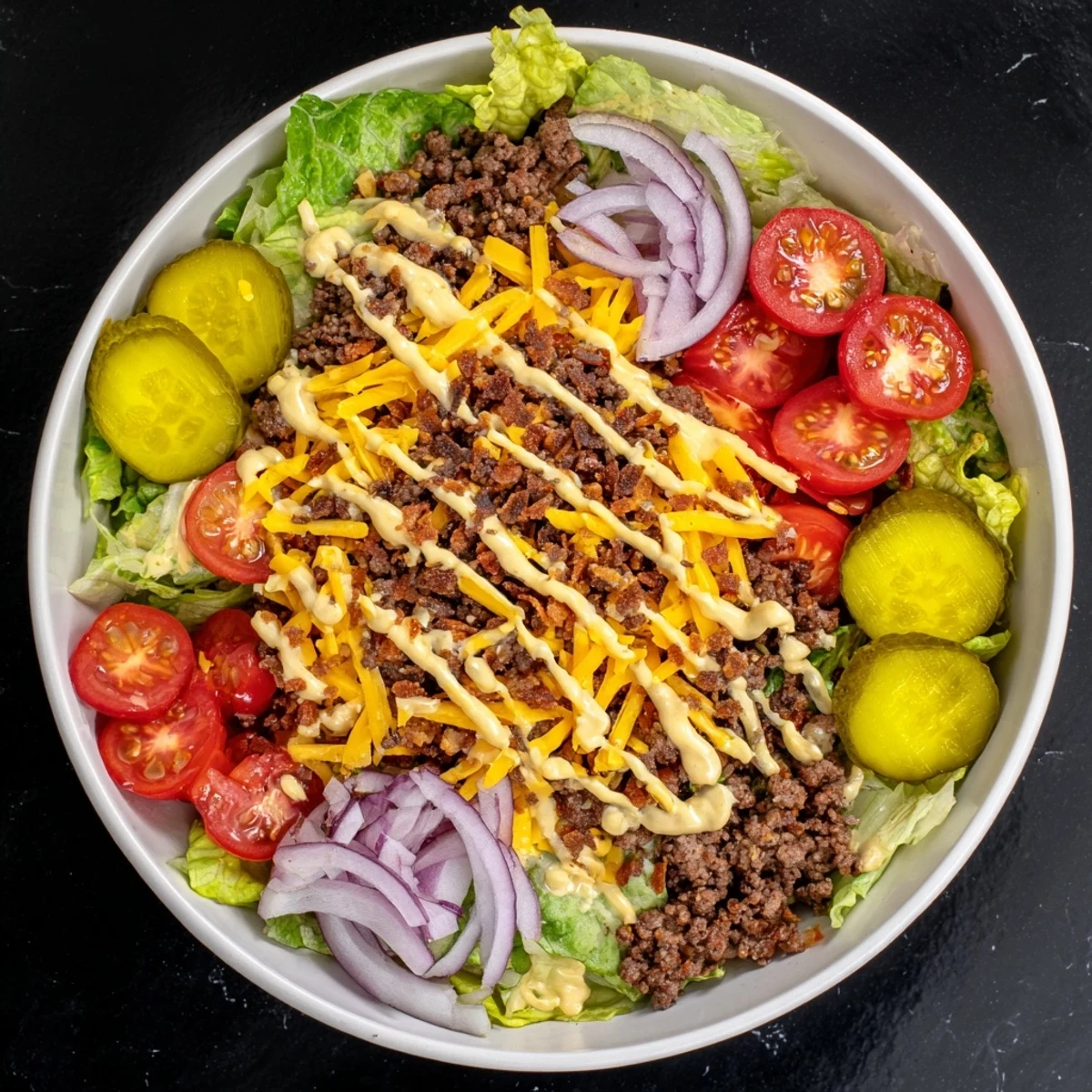 Bowl of savory burger mixture with romaine lettuce tomatoes pickles and drizzled sauce offering a quick healthy American meal alternative