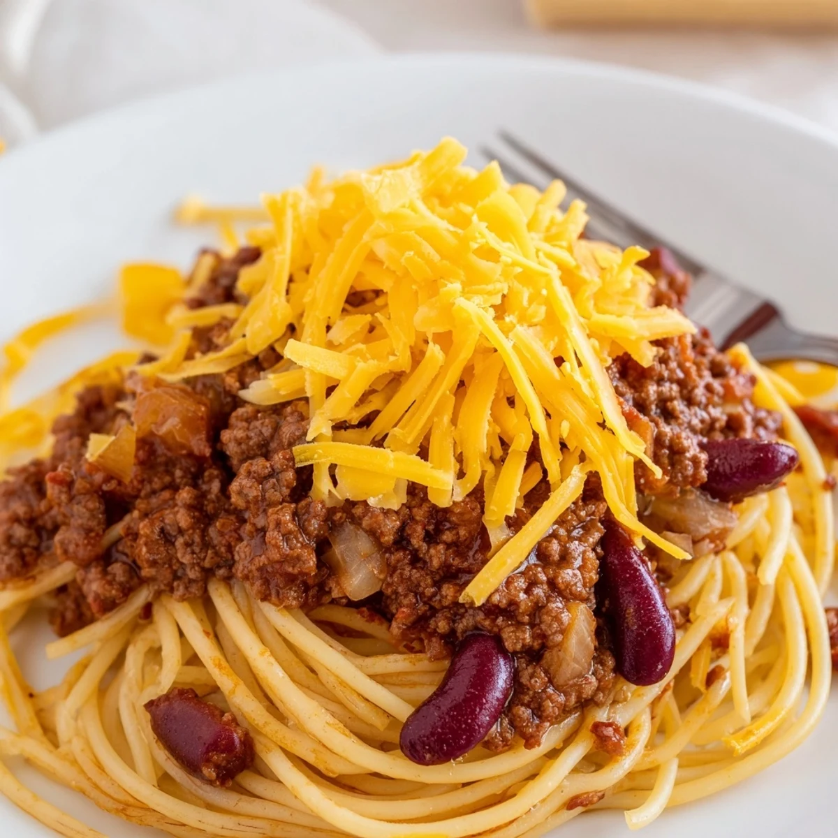 Savory Cincinnati chili poured over spaghetti noodles with generous cheddar cheese and fresh onion toppings