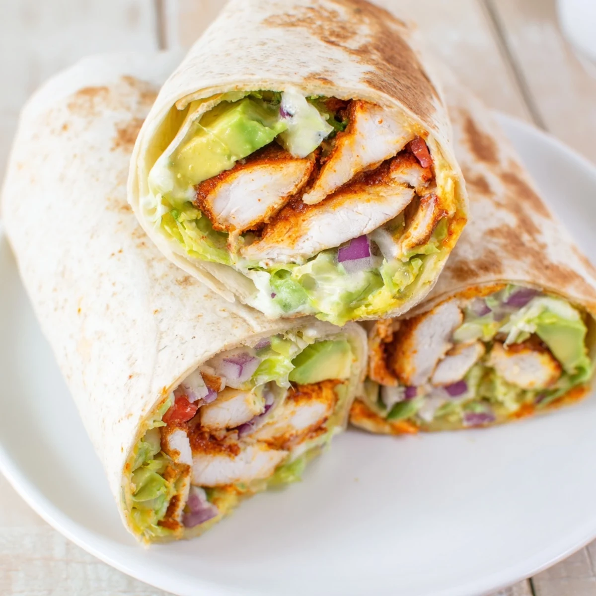 Fresh spicy chicken avocado wraps rolled with tender seasoned chicken, ripe avocado slices, and colorful lettuce and tomato