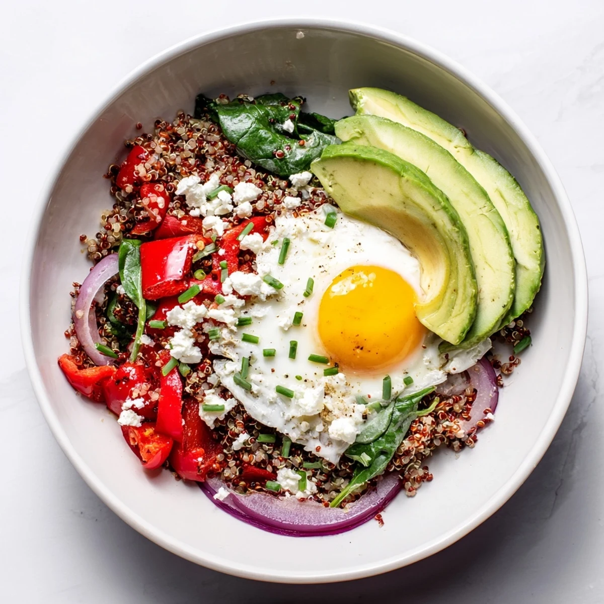 Hearty savory quinoa breakfast bowl in white serving dish garnished with fresh herbs and avocado