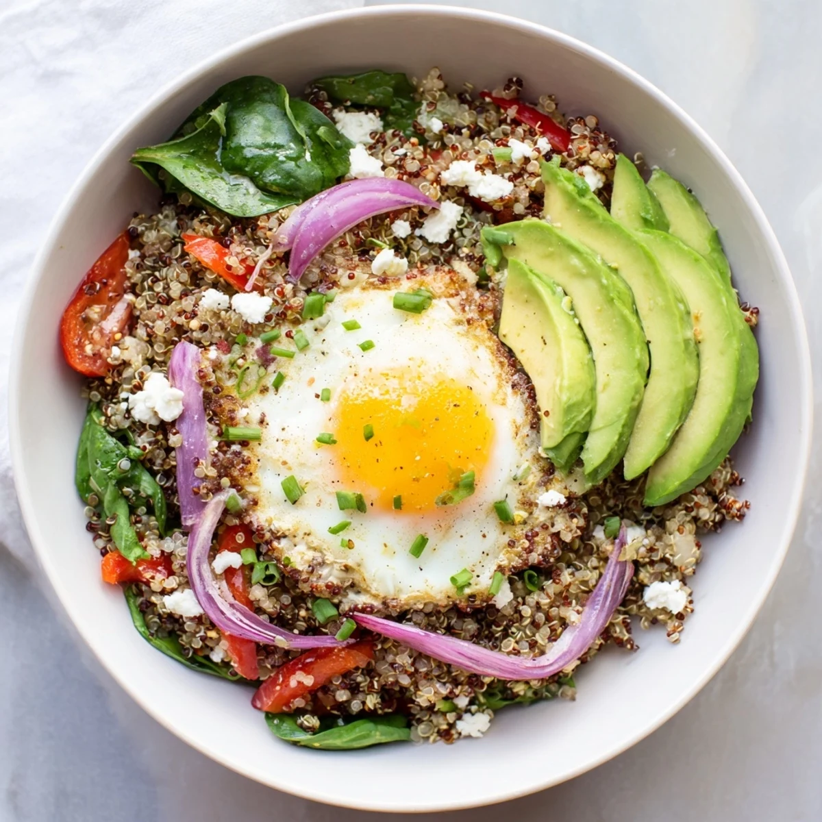 Protein-rich savory quinoa breakfast bowl featuring spinach, bell peppers, tomatoes, and perfectly cooked egg