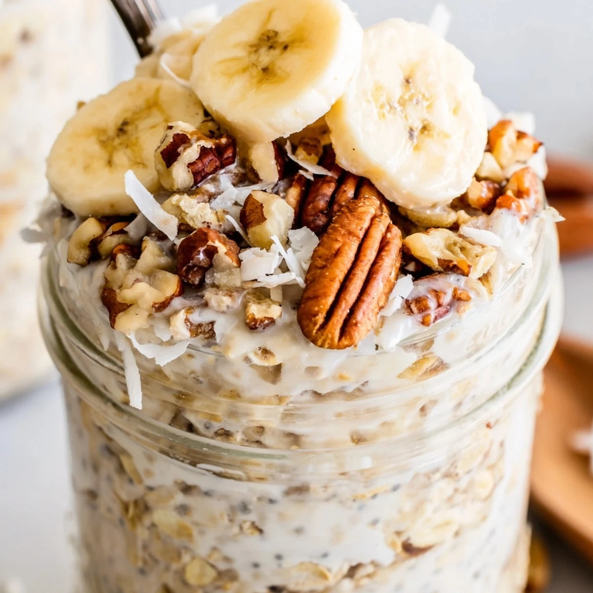 Coconut Cream Pie Overnight Oats in a mason jar with banana slices