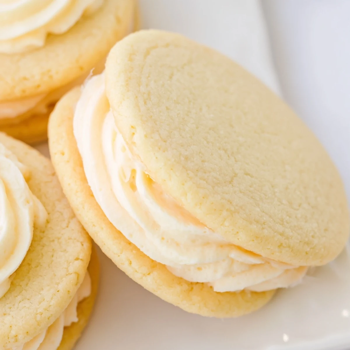Delicate sugar cookie sandwiches showcasing layers of pink blue and green buttercream frosting
