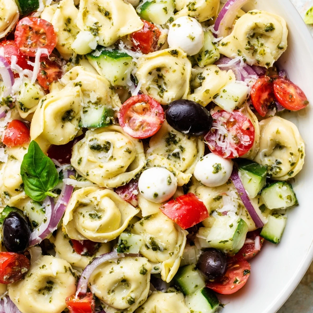 Creamy cheese tortellini salad tossed with crisp vegetables and fresh basil, ready to serve