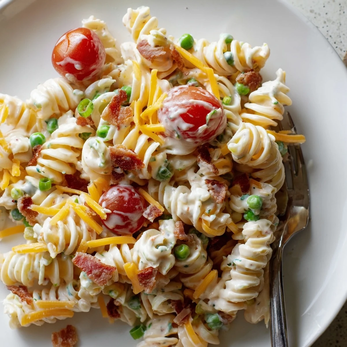 Creamy addictive crack pasta salad topped with cheddar cheese bacon bits and cherry tomatoes