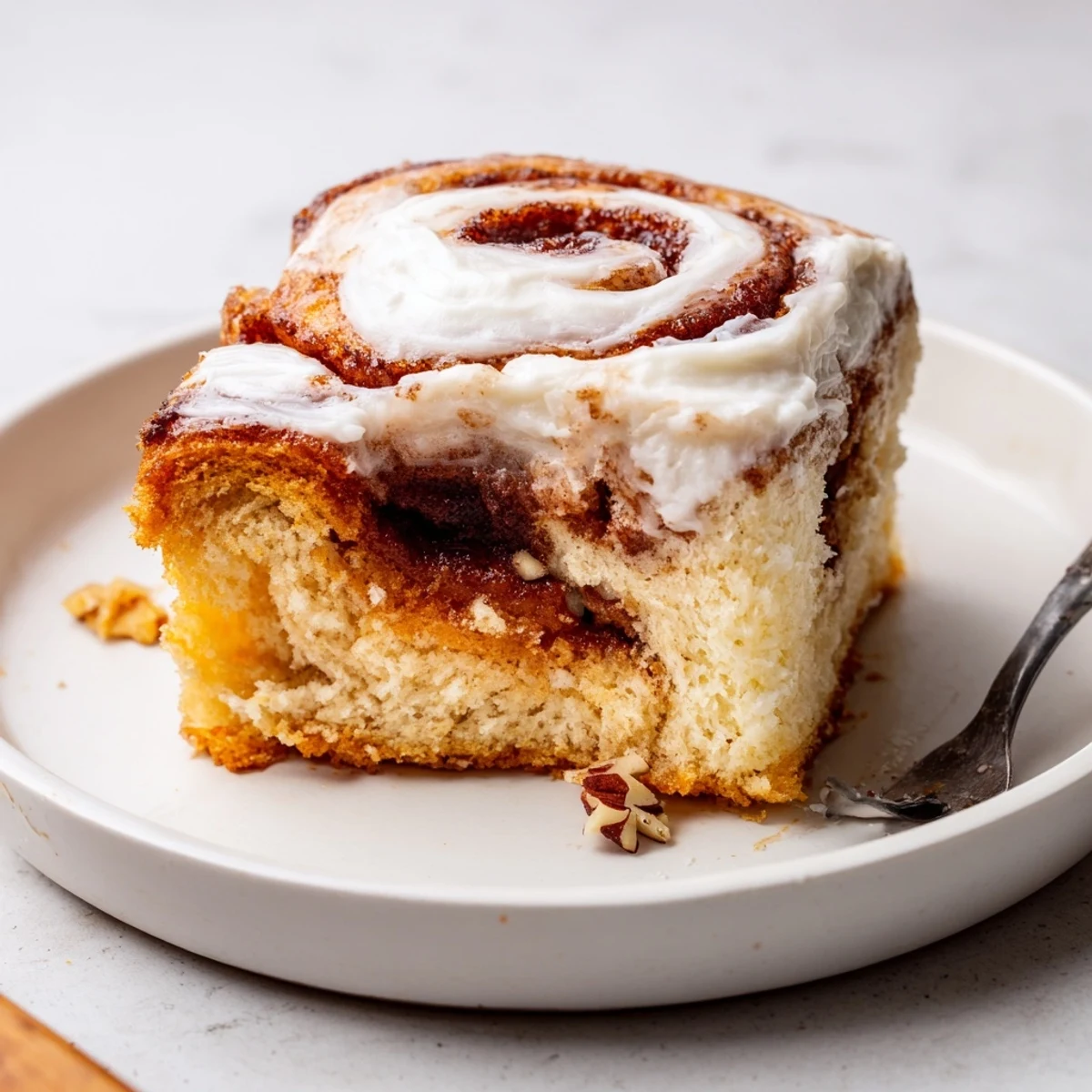 Slice of Cinnamon Roll Poke Cake topped with velvety frosting and pecans
