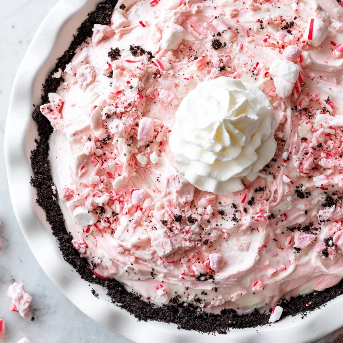 Slice of Candy Cane Pie revealing pink peppermint swirls, marshmallows, crumbly crust.