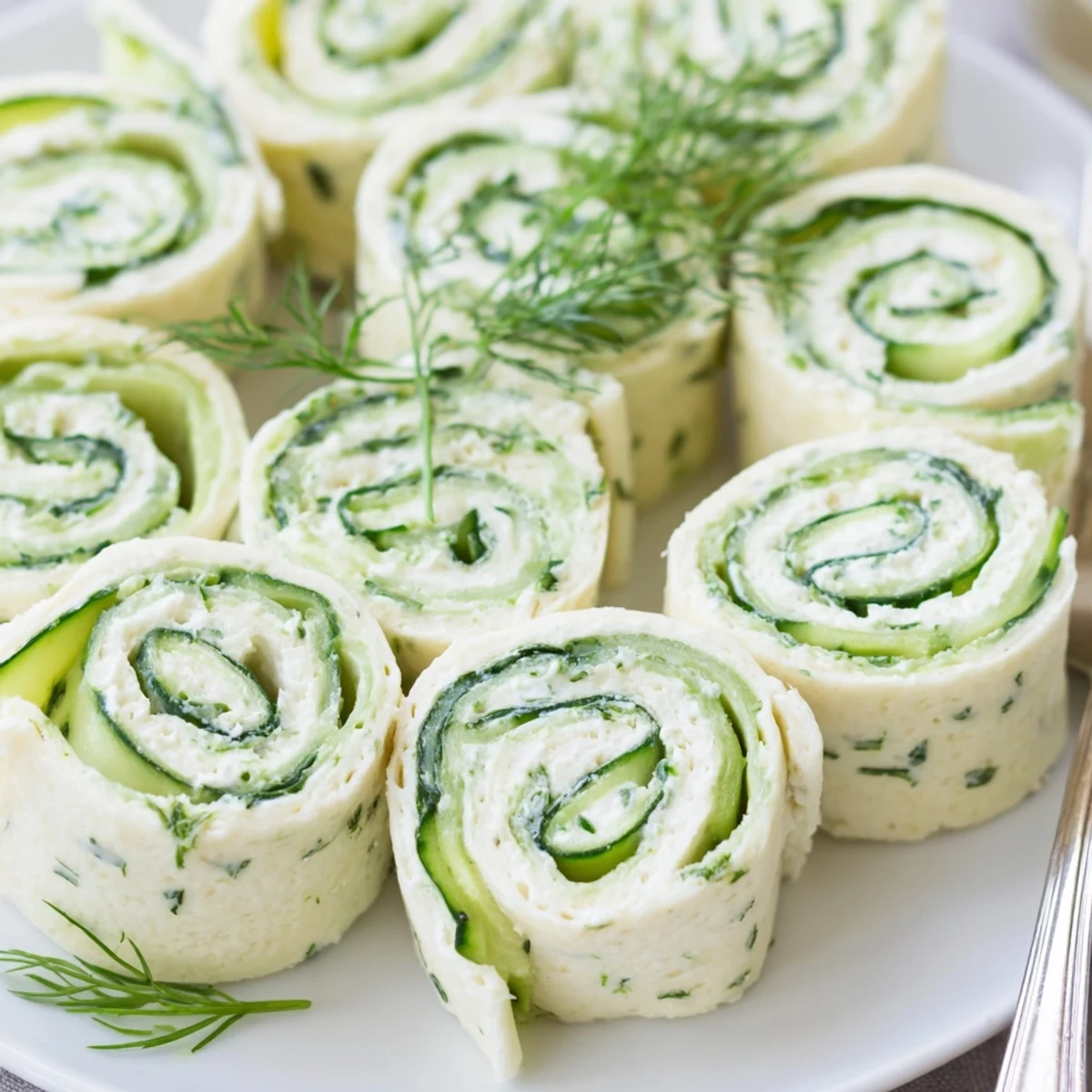 Cucumber And Dill Pinwheels on a platter, creamy spread and crisp slices  