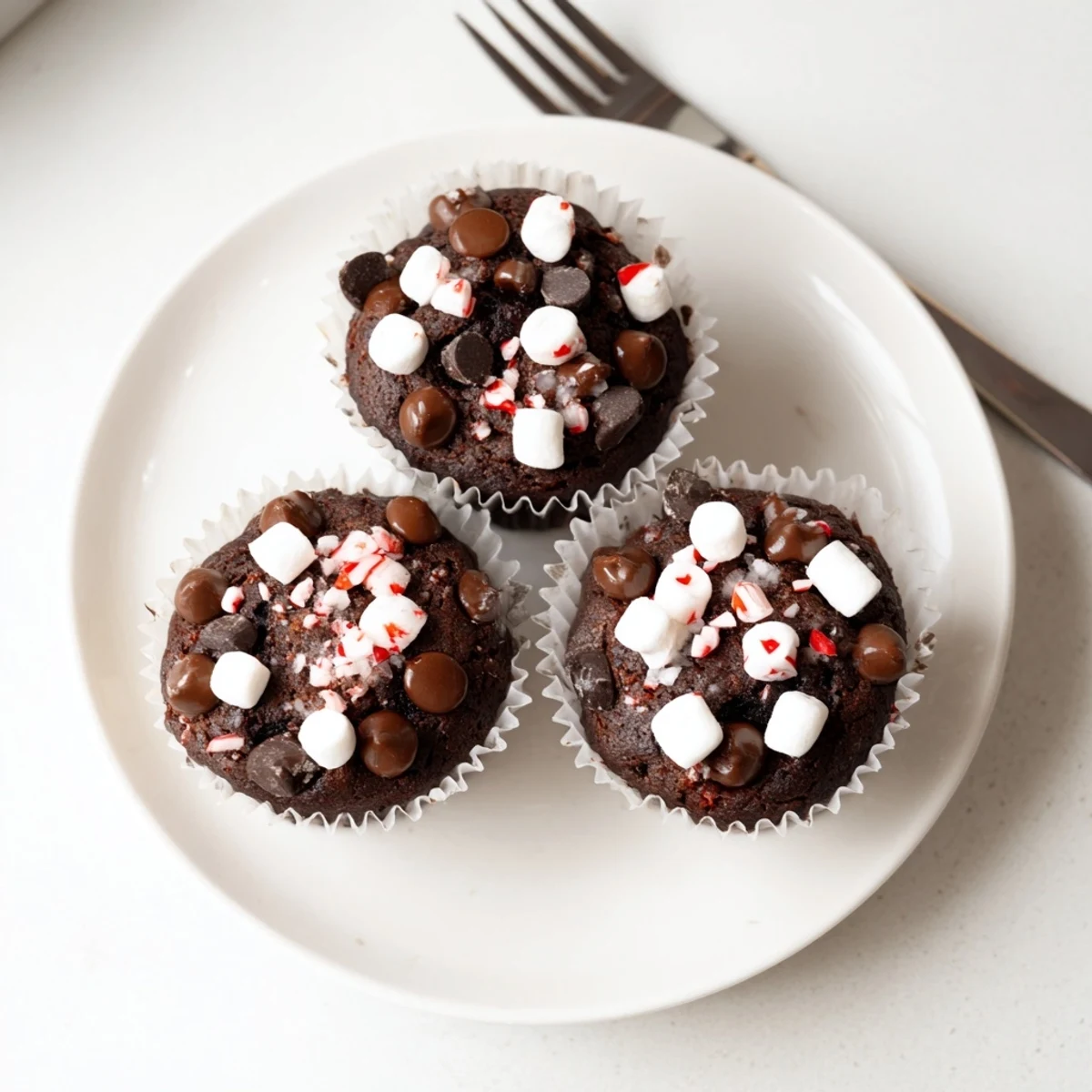 Fresh-baked Peppermint Hot Chocolate Muffins lined in paper, steaming on a rack  